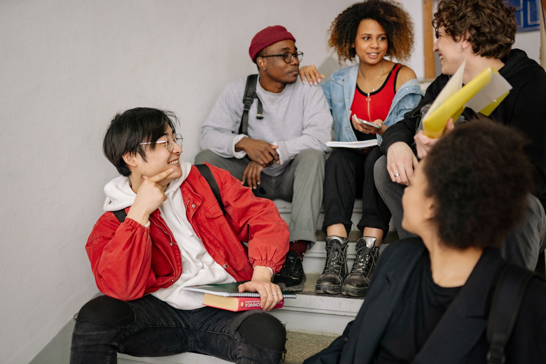 A group of young adults sitting on stairs, talking