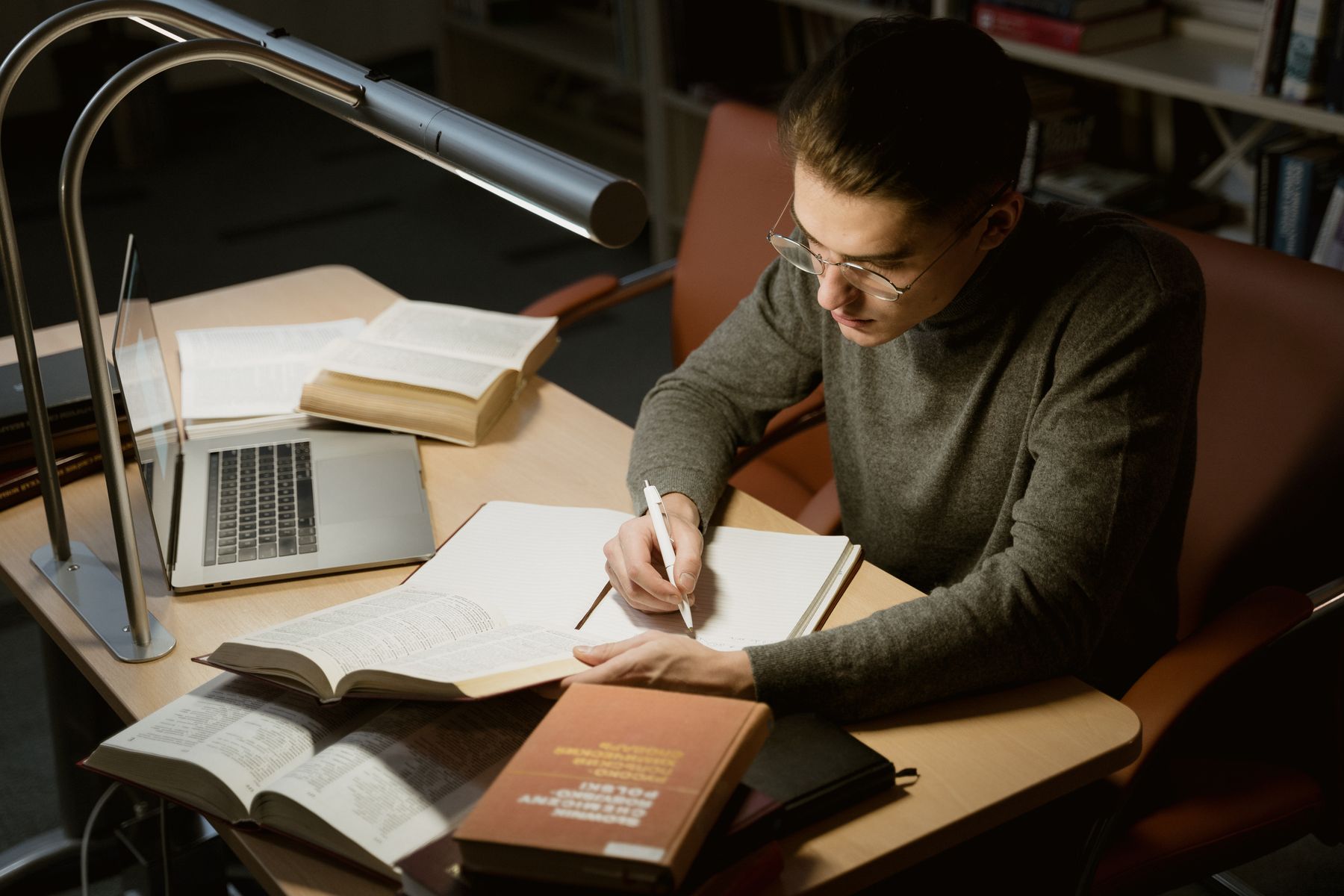 Young man studying with books and a laptop